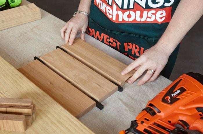 A person arranging three lengths of timber with spacers in between them