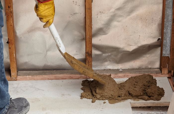 Concrete being shovelled onto the floor where a shower base will be laid