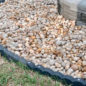 Large pebbles fill a fire pit space within flexible garden edging