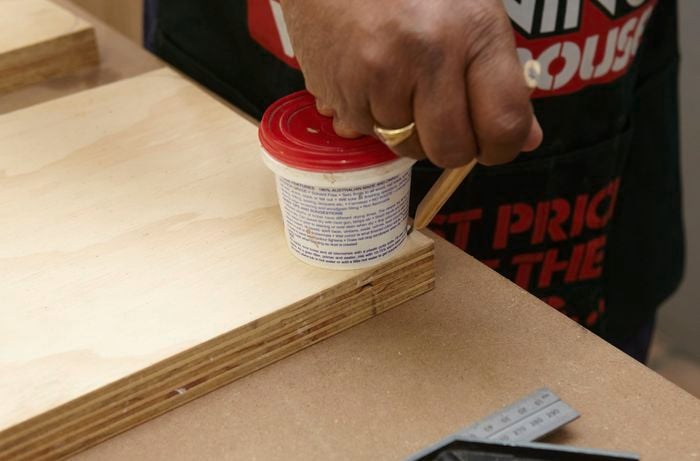 Person using pencil to draw an outline around a small tub sitting on piece of ply wood.