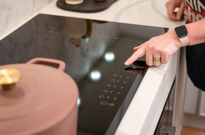 A woman pointing her finger to the electric cooktop.