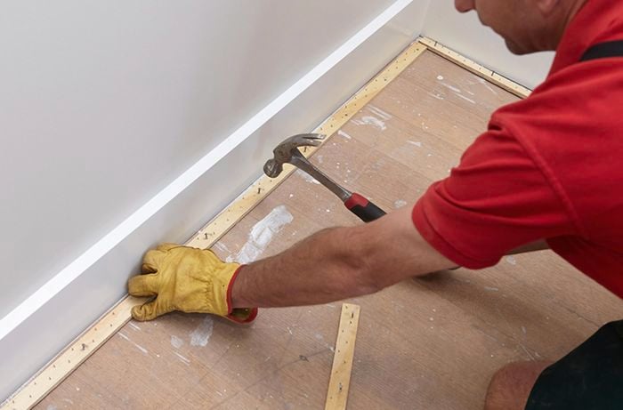 A perimeter of smooth edge being nailed down to subfloor by a Bunnings team member