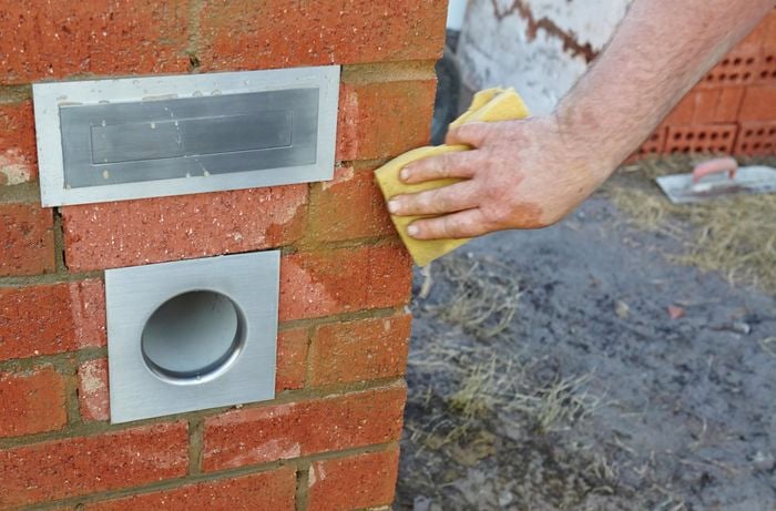 Excess concrete being cleaned off the sides of a brick letterbox
