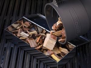Woodchips being loaded into a gas BBQ for smoking meat and fish