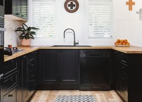 kitchen with black cabinets and appliances, white walls and plantain shutters