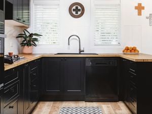 kitchen with black cabinets and appliances, white walls and plantain shutters