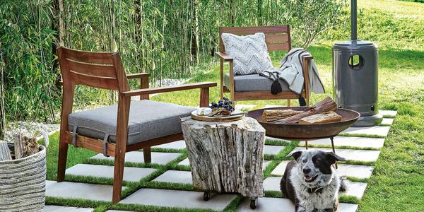 Outdoor armchairs on pavers next to a firepit and gas heater