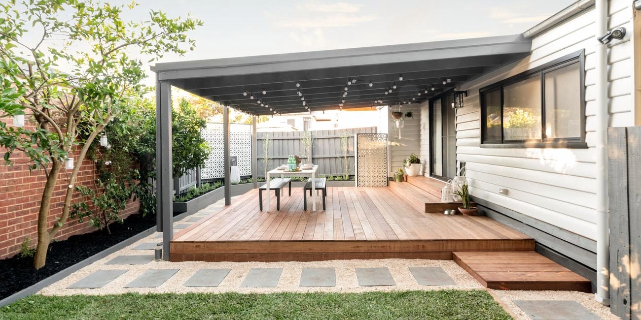 Pergola with decking, outdoor setting and string lights.