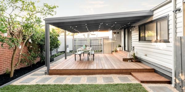 Backyard pergola with decking, pavers and trees.