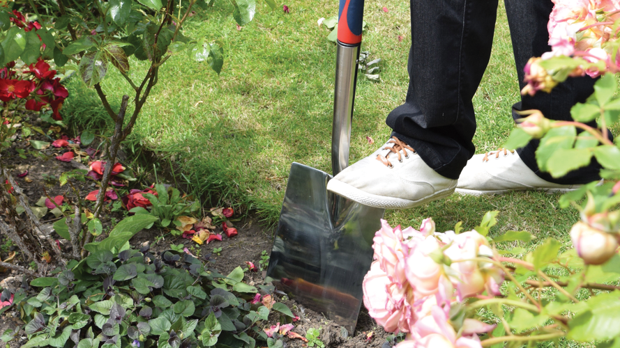 Close up of person digging a spade into a garden bed