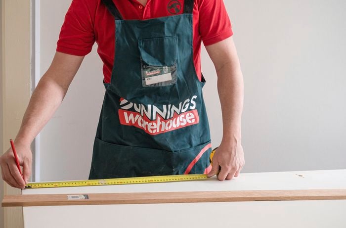 A person measuring the length of the trim.