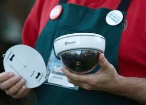 A person holds two wireless Swann security cameras.