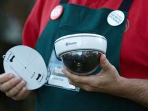 A person holds two wireless Swann security cameras.