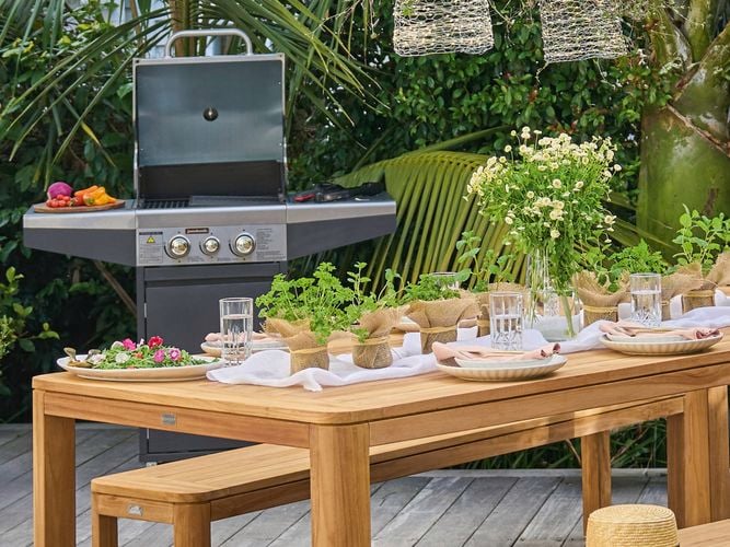 Backyard outdoor dining setting with a jumbuck BBQ in the background
