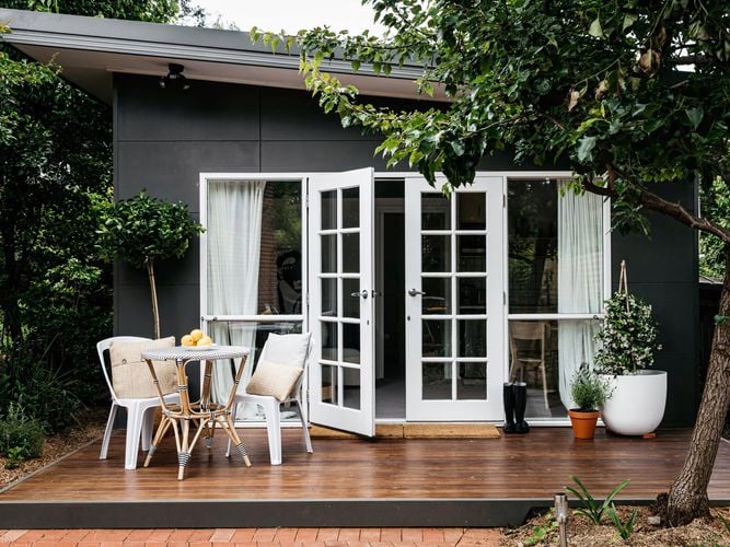 Granny flat with wooden porch with outdoor table/chairs set and plants