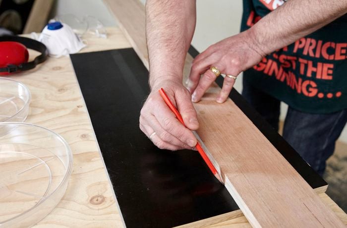 A person marking the centre line on a piece of plywood