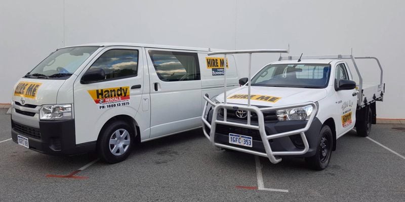 A rental van parked next to a ute. The vehicles are branded for Handy Rentals.