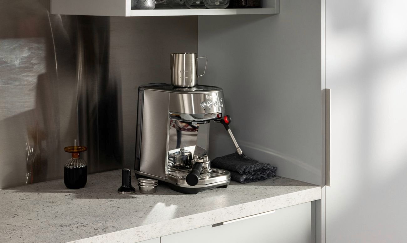 A mid shot of a kitchen benchtop and cupboard with a coffee machine in the centre of the image.