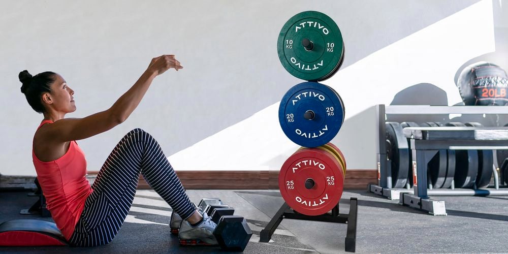 A lady exercising in front of an Olympic rack barbell.