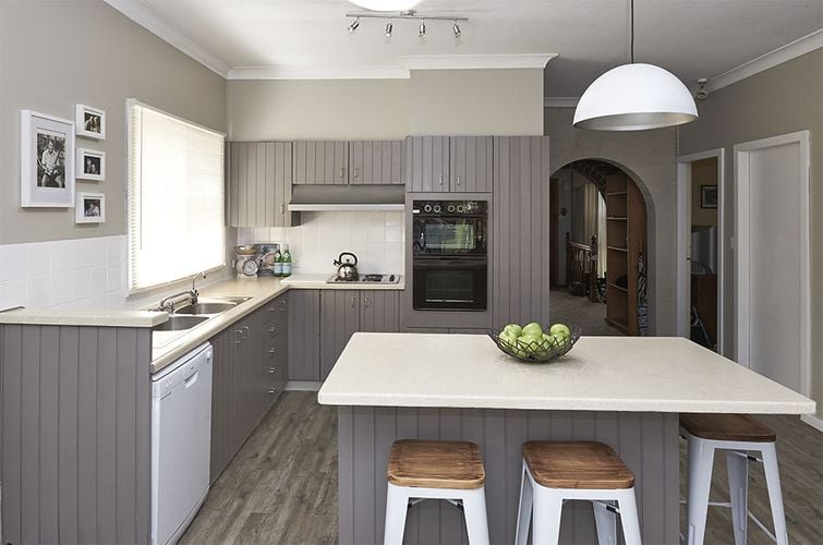 A warm grey kitchen area, with a bowl of apples on the island in the middle