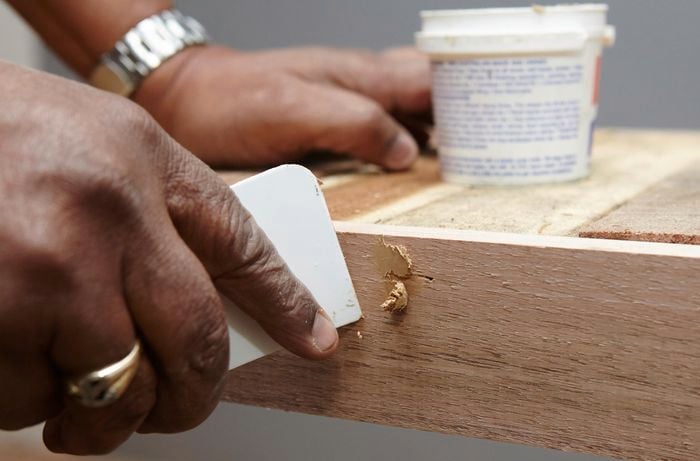 Person apply putty to cover nail holes
