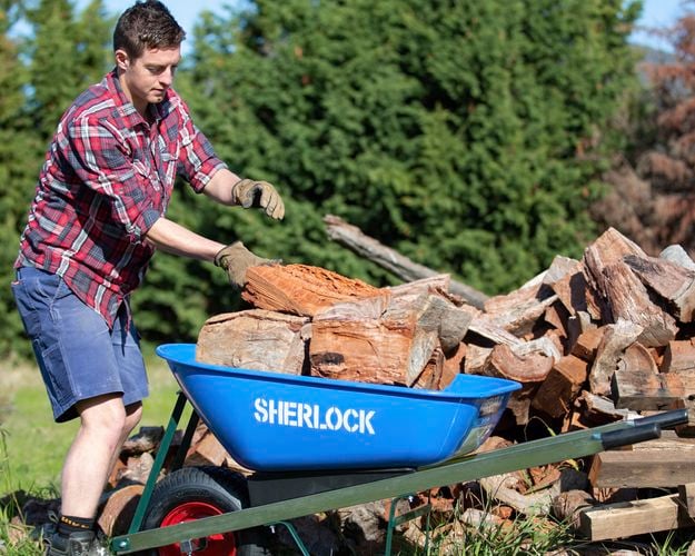 Tradesperson loading wheelbarrow with chopped wood