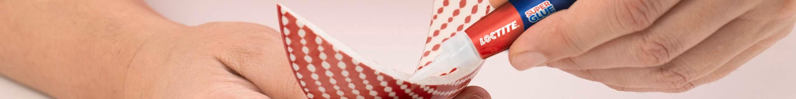 A close up of a person applying Loctite superglue to broken ceramic.