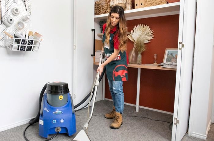 A woman in Bunnings uniform steam cleaning a carpet