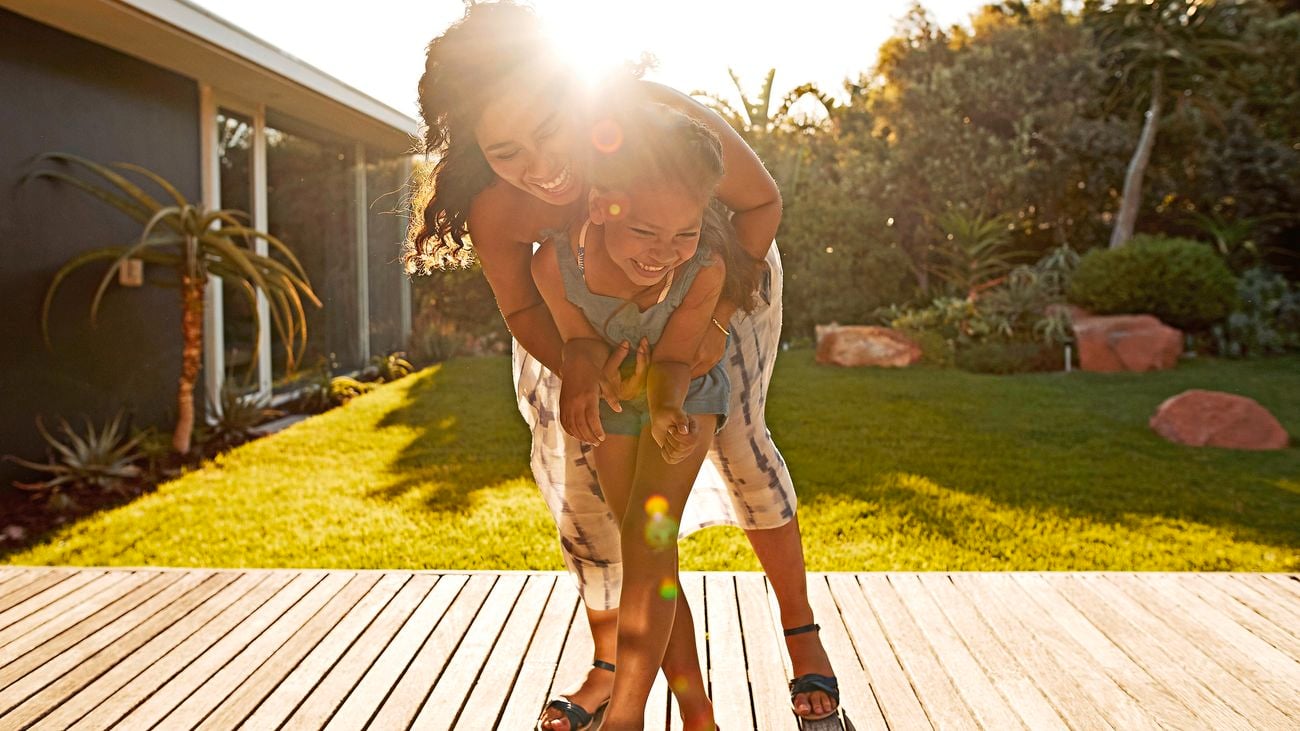 Mother and daughter playing on a deck in the sun.