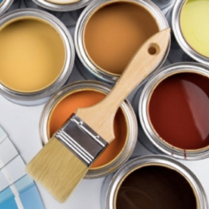 Lots of different coloured paint swatches, paint tins and a paint brush on a flat surface.