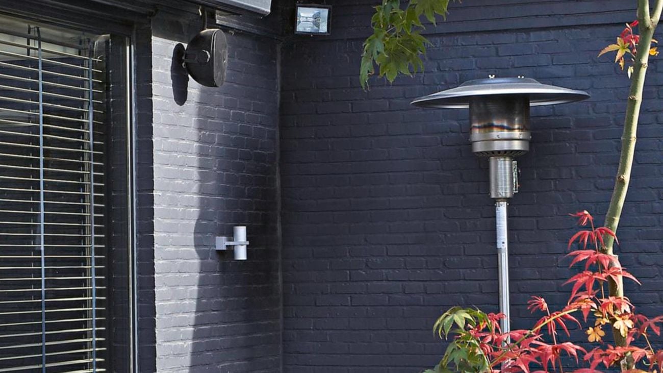 The Fiammetta outdoor gas patio heater outside a dark grey house.