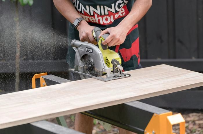A Bunnings Team Member using a circular saw on a piece of wood