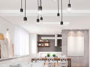 Modern lounge and dining area with a white and cream colour scheme. The space is accompanied by wooden floorboards, concrete feature walls and pendant lights hanging from the ceiling.