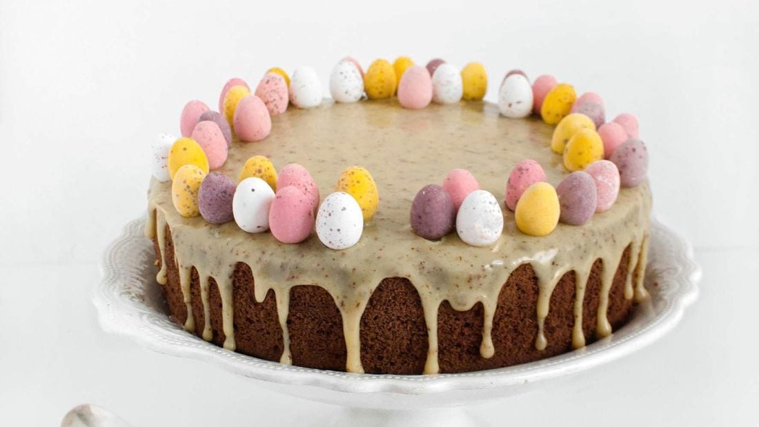 Chocolate cake decorated with Easter eggs on stand with white background.