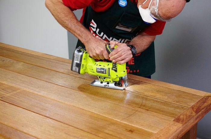 Person using jigsaw to cut a large hole in table top.