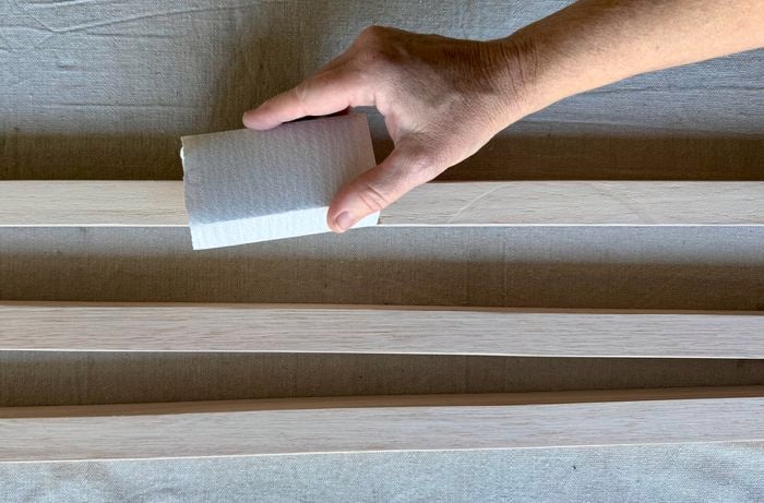 A hand sanding the slats.