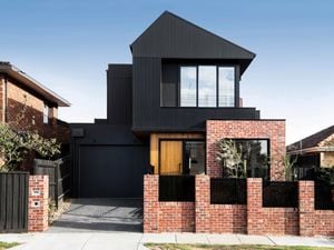 Modern two-story house with a black timber and exposed brick exterior