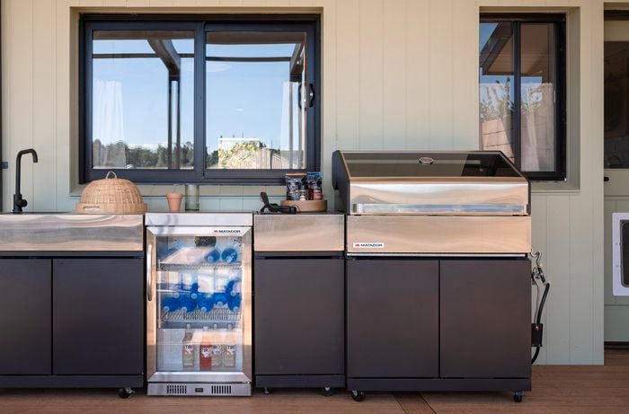 Outdoor kitchen with a fridge, BBQ and basin in it