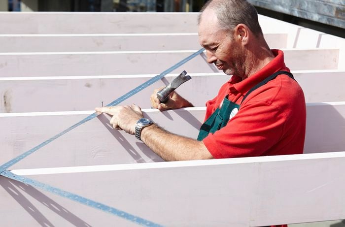 A person attaching metal cross bracing diagonally across rafters