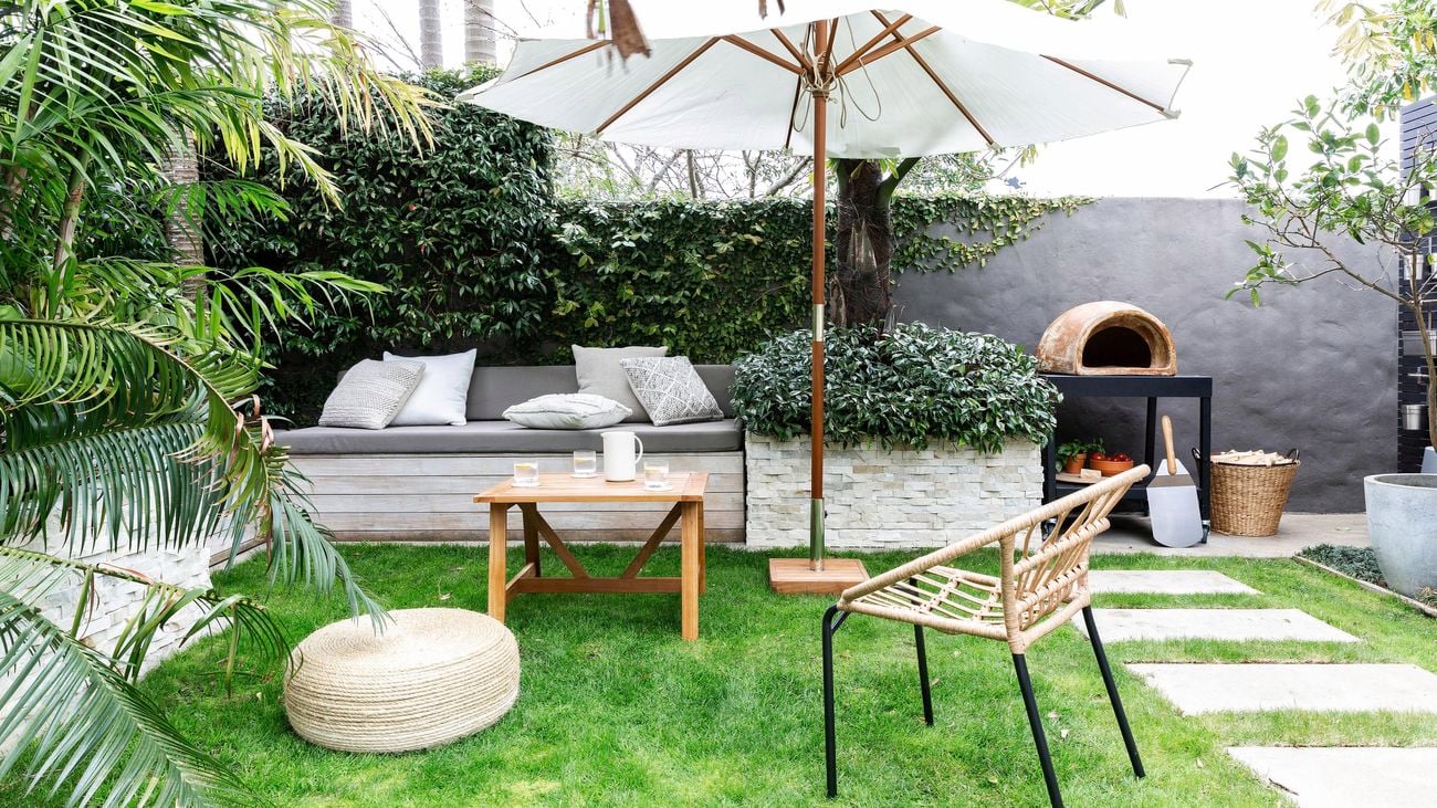 Luscious well maintained green lawn, with a shade umbrella and beachy outdoor furniture