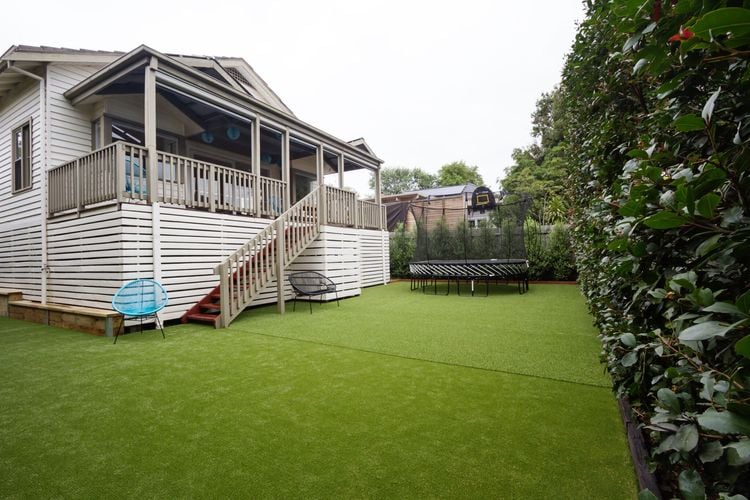A backyard lawn with trampoline in front of a deck