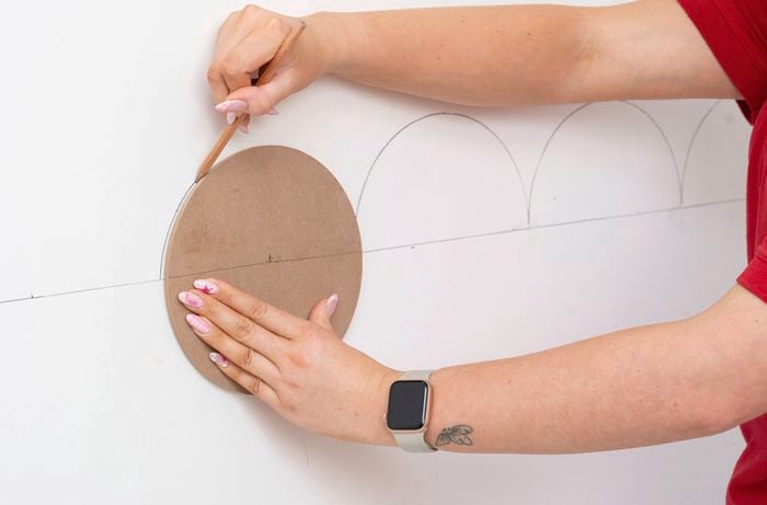 A person is tracing the curved edge above the line to form a semi-circle for the scalloped pattern