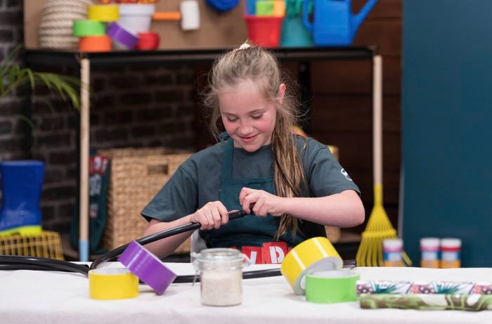 A smiling girl is connecting a hula hoop tube at a Bunnings DIY workshop.