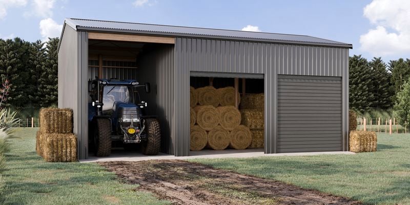 Large grey farm shed with a tractor and hay bales.
