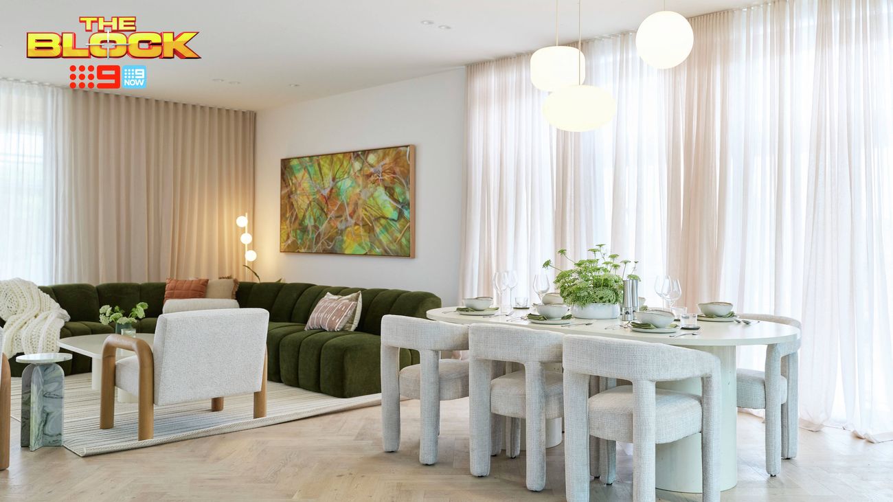 Open-plan living and dining area featuring a curved dining table, green sofa, modern pendant lights and floor-to-ceiling sheer curtains.