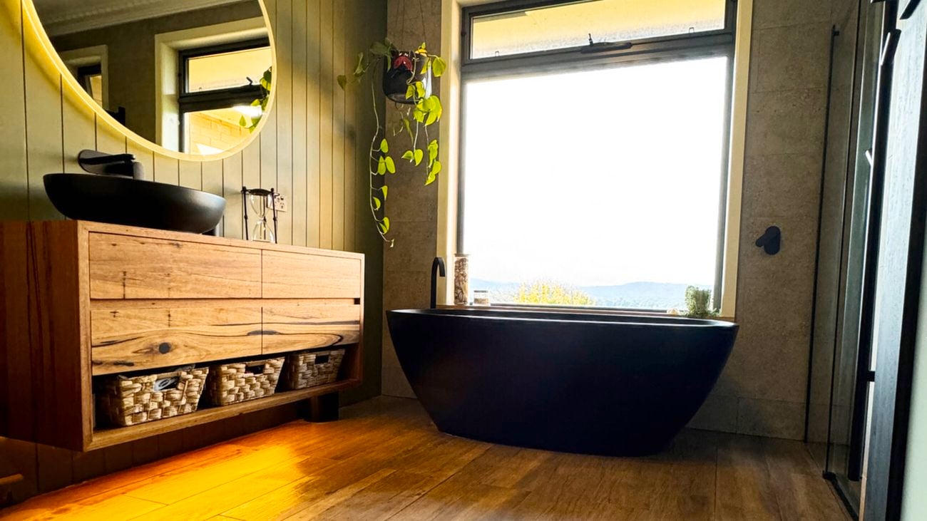 renovated bathroom with new polished timber floors, black free standing bath,  black basin sitting on timber vanity.