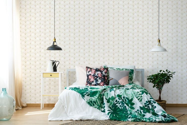 Bedroom with Graham & Brown wallpaper, bed with light coloured furnishings and two-bedroom hanging lights.