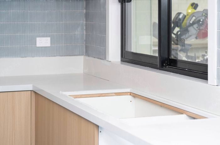 A kitchen benchtop has been installed with a cut-out section prepared for a sink.