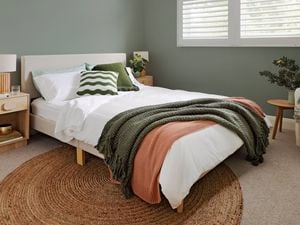 Modern bedroom with timber furniture and green walls.