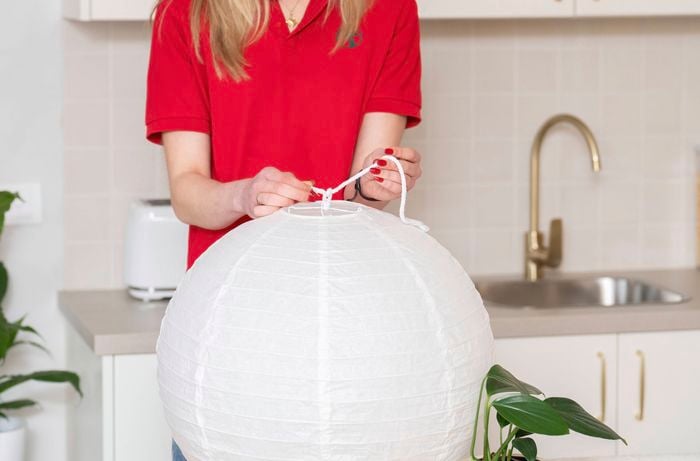 A Bunnings Team Member is attaching a hanging cord to a lightweight pendant shade.